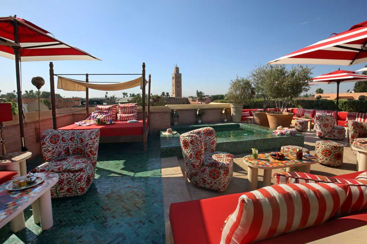 Rooftop d'El Fenn à Marrakech avec vue sur la Koutoubia, transats rouges et parasols rayés
